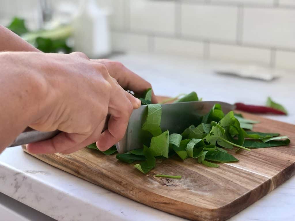 nasturtium leaves being cut on a chopping board