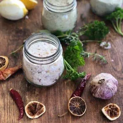 jars of salt on a wooden board with garlic, herbs and dried chilli
