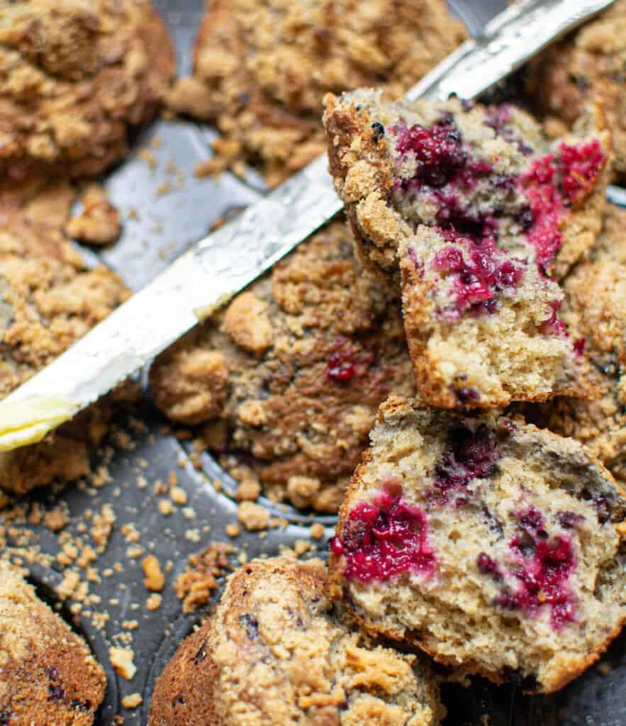 Blackberry Streusel Muffins in muffin trays with one cut in half with a knife