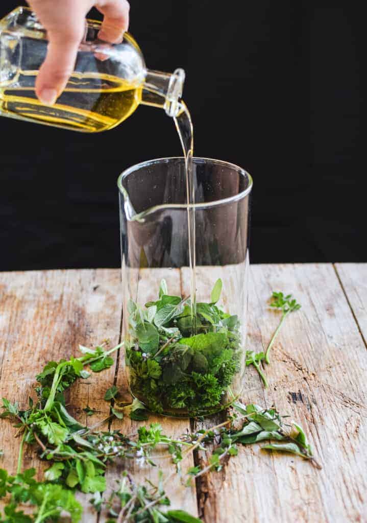 Olive oil being poured over top of herbs 