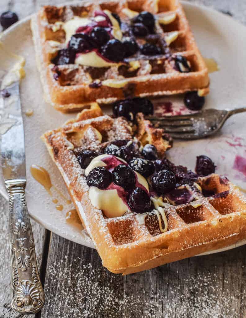sourdough waffles on a plate topped with blueberries and cream 