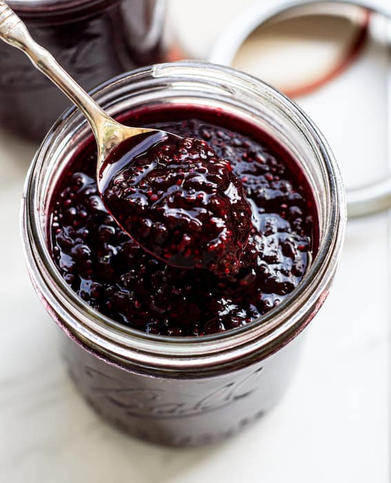A jar of jam with a spoon in it scooping it out