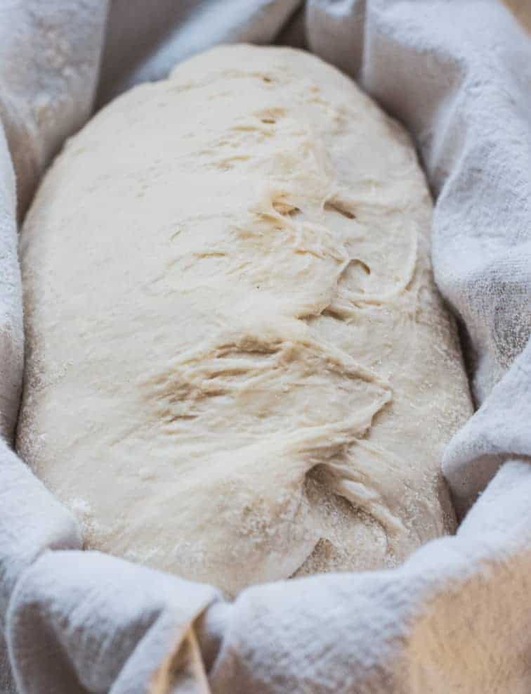 sourdough dough in a floured towel in a banneton basket