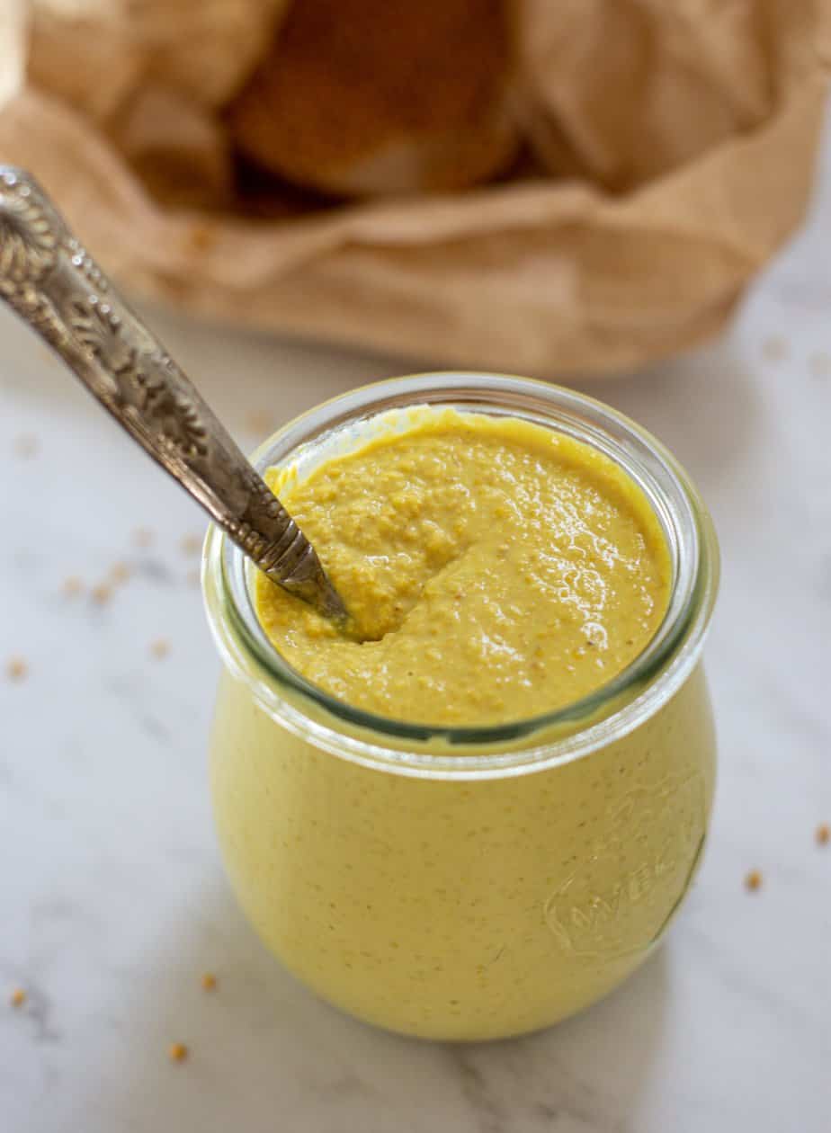 a small jar of yellow mustard with a spoon in it