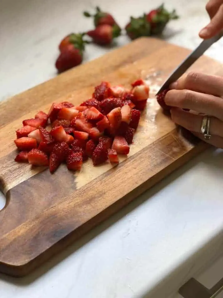 strawberries being chopped on a wooden board