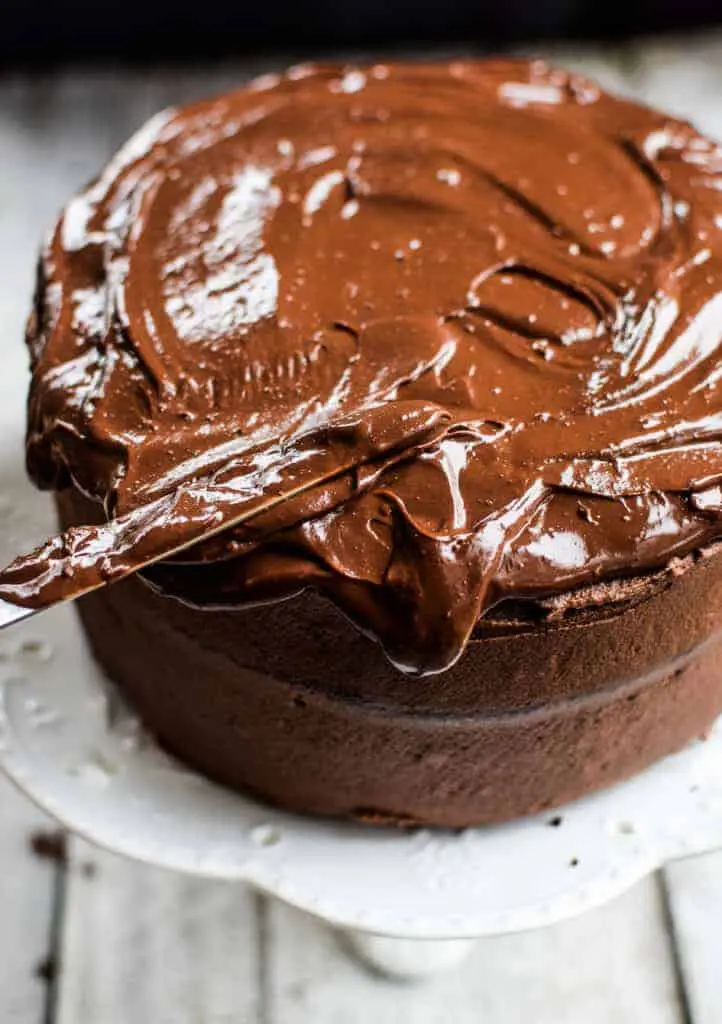 a knife spreading chocolate ganache on a cake