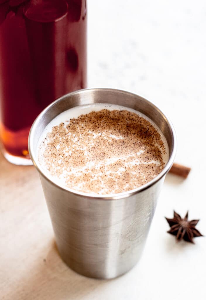 a close up f milky chai tea a cinnamon stick and star anise in the background