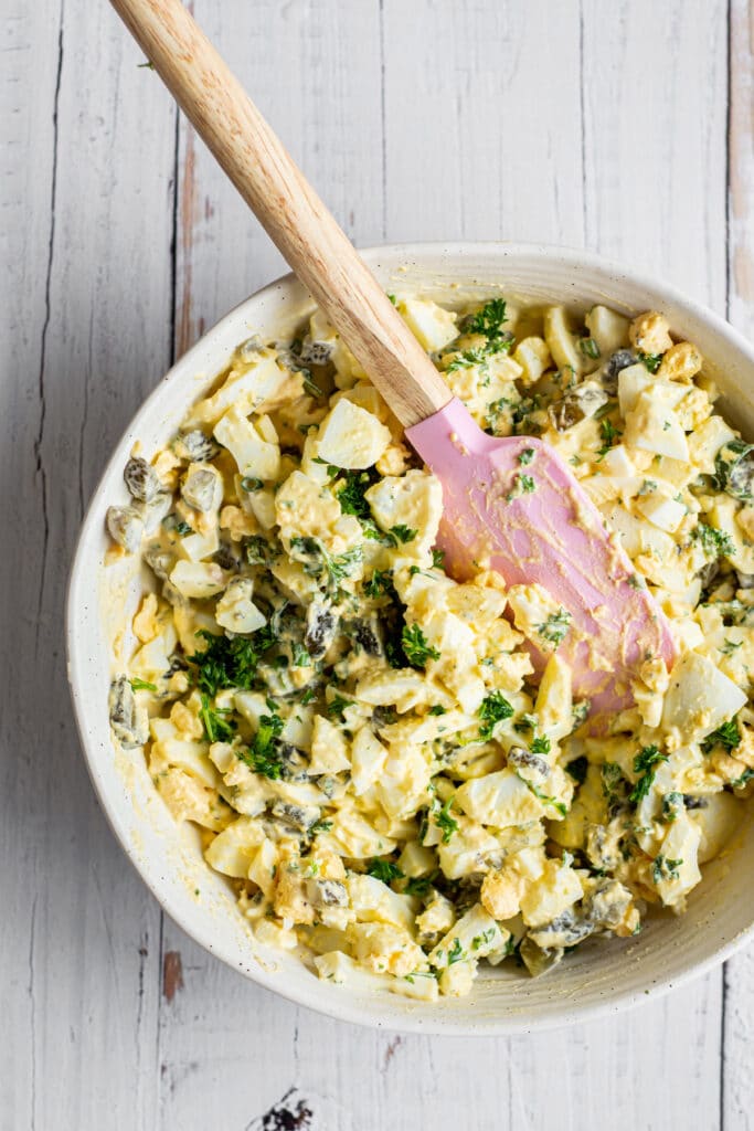 a bowl of egg salad with pickles and parsley