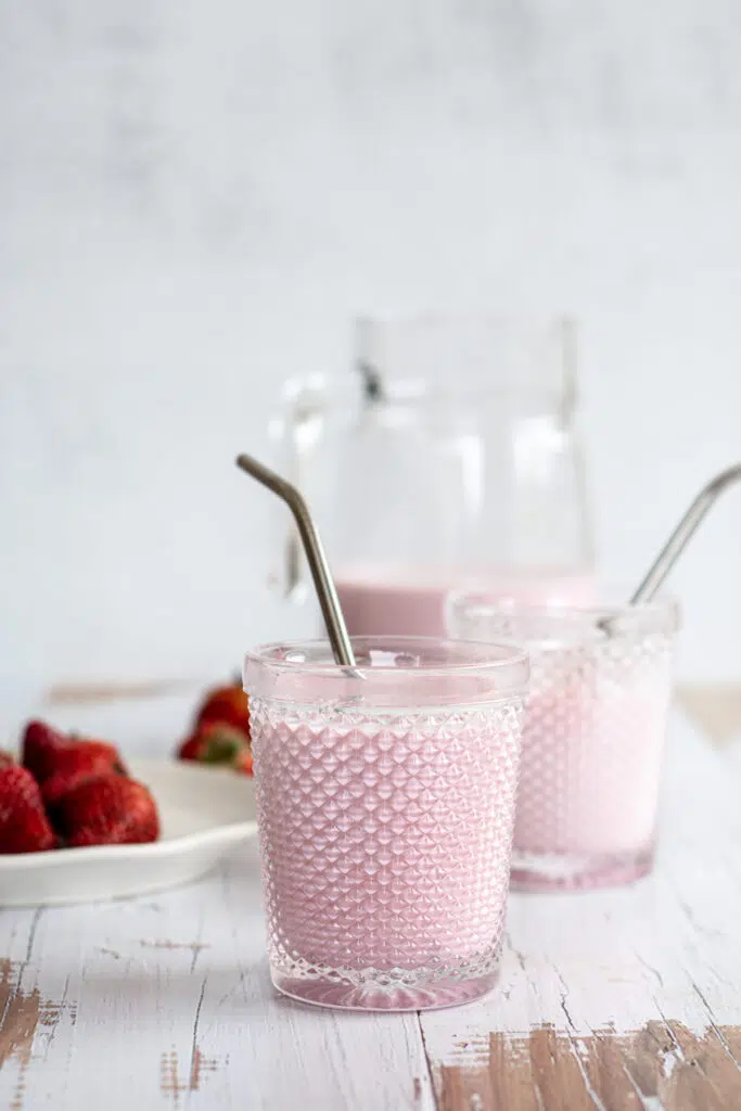 glasses of pink strawberry milk on a wooden backgriund